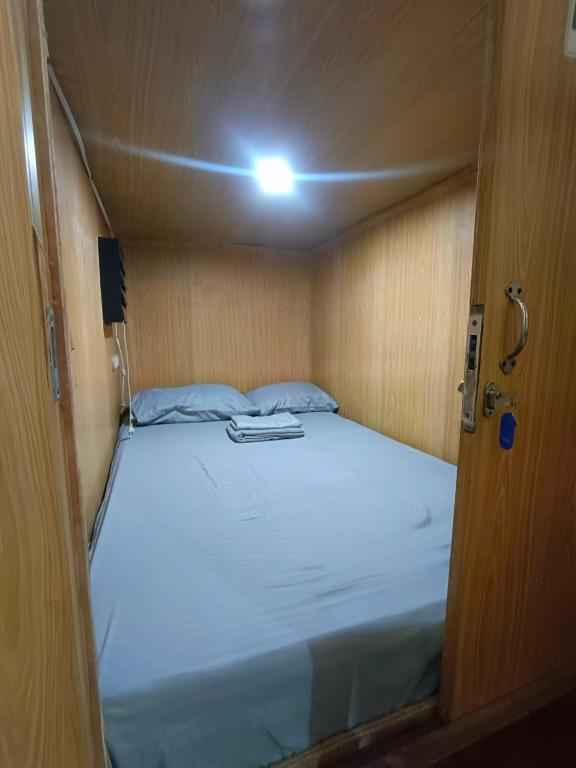 a bed in a small room with a light on it at Metro Capsule Rental in Manila