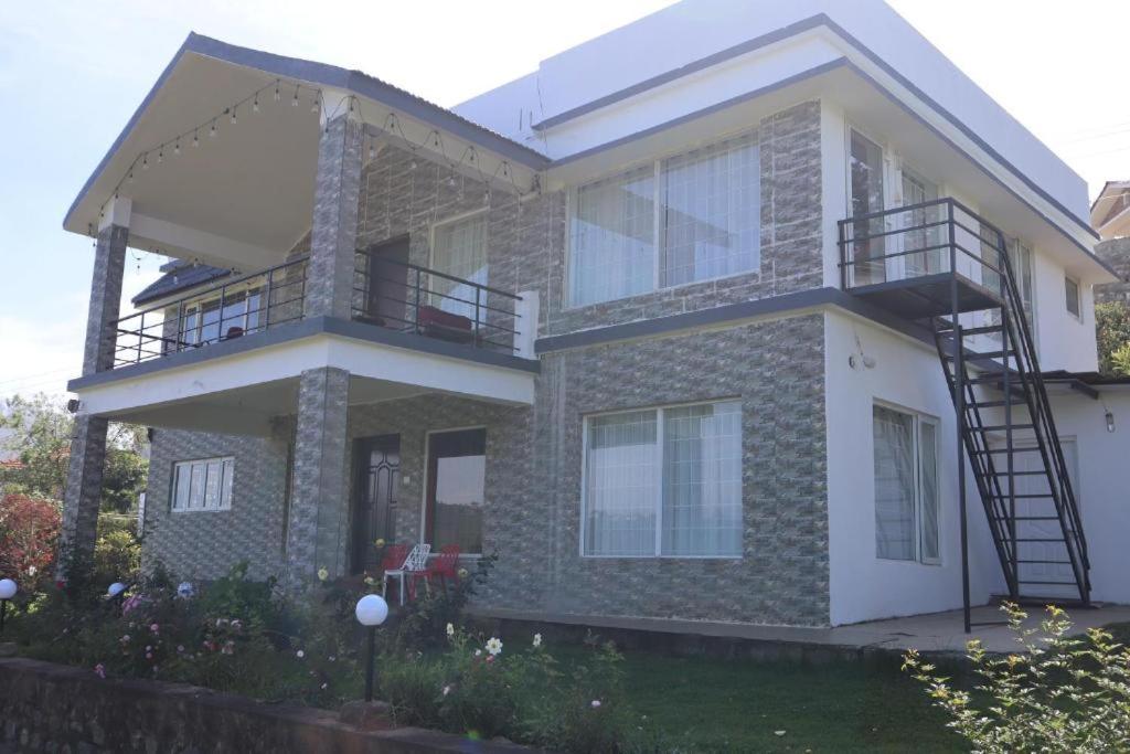 a house with a balcony on top of it at Rakas Guest House Ooty in Ketti