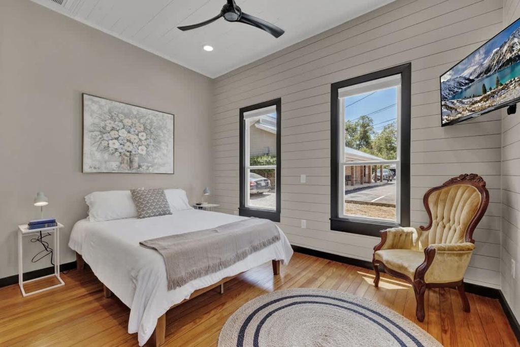 a bedroom with a bed and a chair and windows at Historic Gem near Schlitterbahn in New Braunfels