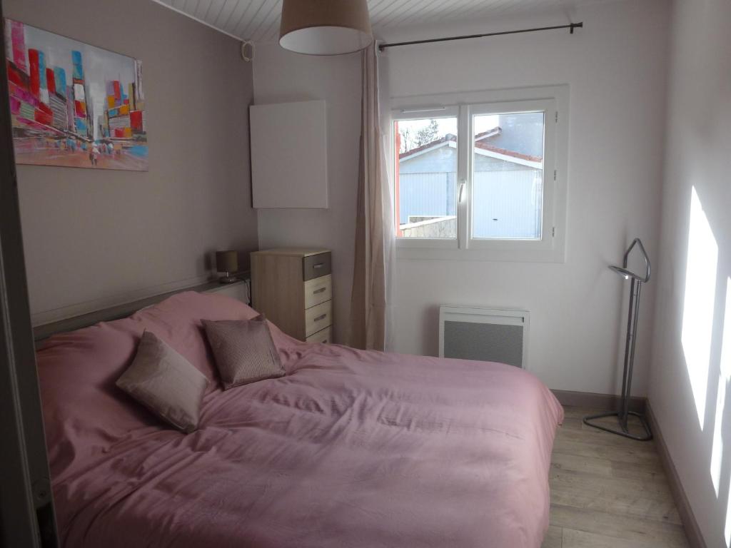 a bedroom with a pink bed with a window at Appartement proche Centre et Arènes in Dax