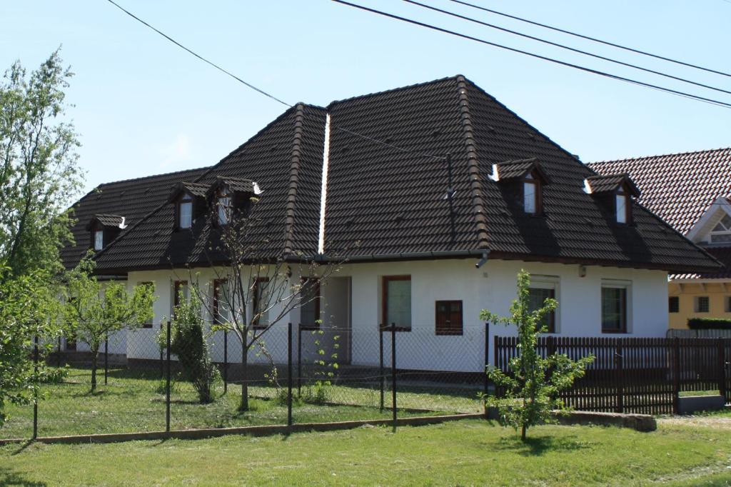 a white house with a black roof at Családfa Vendégház in Ságvár