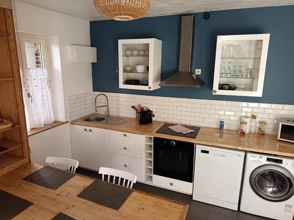 a kitchen with white cabinets and a blue wall at La Maison du Bonheur au Coeur d'Etretat in Étretat