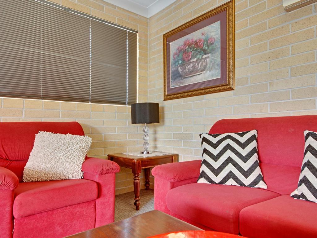 a living room with two red couches and a table at Murray Street Apartments in Rockhampton