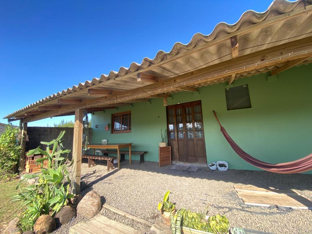 a green house with a wooden pergola at Casa de Férias Balneário Gaivota in Balneário Gaivotas