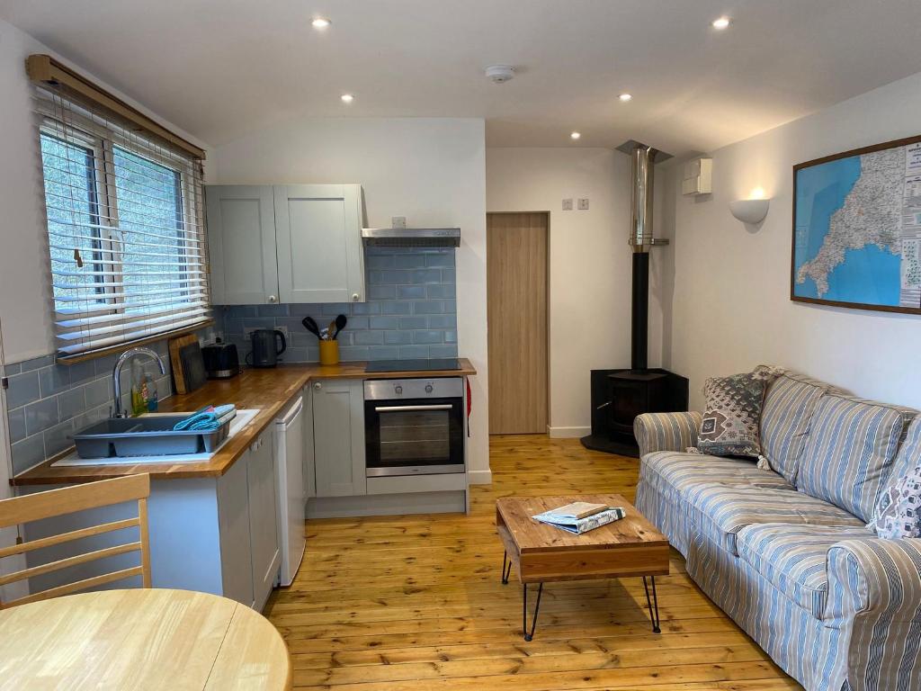a kitchen and living room with a couch and a table at Foxglove cabin in Bodmin