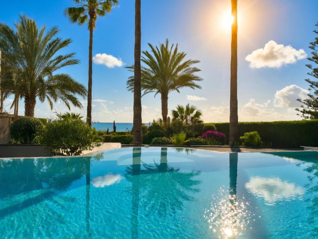 a swimming pool with palm trees and the ocean at 7 Bdr Villa with Heated Pool & Spa in Mazotos