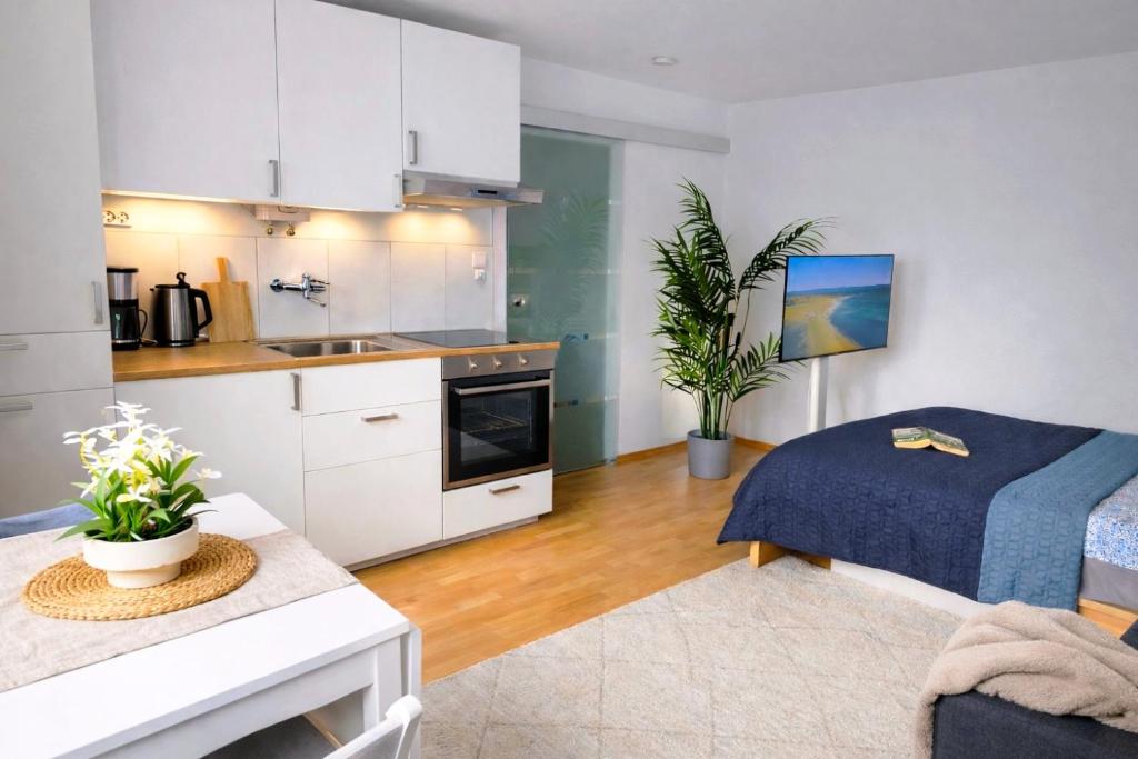 a kitchen and living room with white cabinets and a table at Quiet & Modern Studio near Tram & River Lech in Augsburg