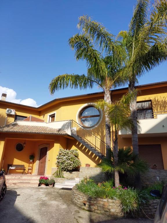 a yellow house with palm trees in front of it at Sikelia in Santa Elisabetta