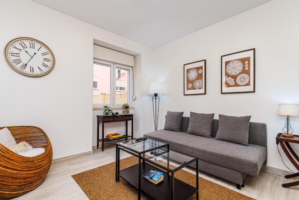 a living room with a couch and a clock on the wall at Doormans House city center by Homeful Homes in Lisbon