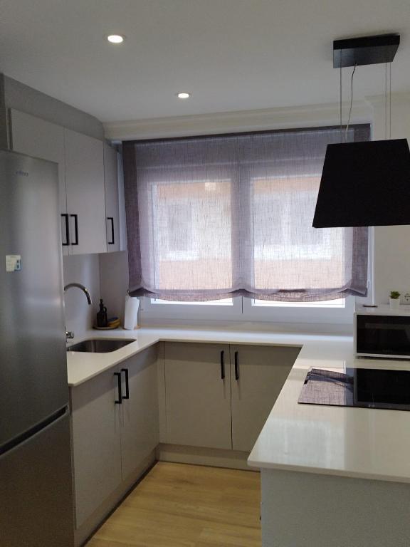 a kitchen with white cabinets and a window at Pretodomar2 in A Coruña