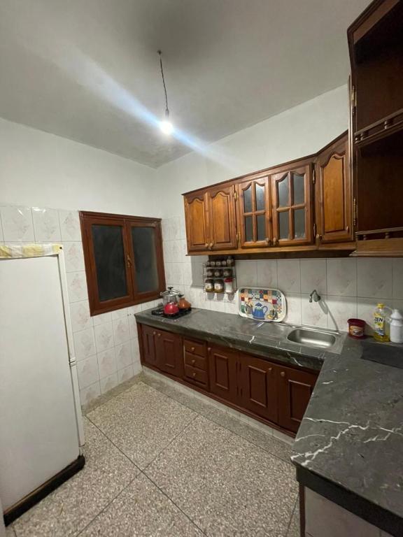 a kitchen with wooden cabinets and a white refrigerator at Appartement Belle vue 3 Meknès in Meknès