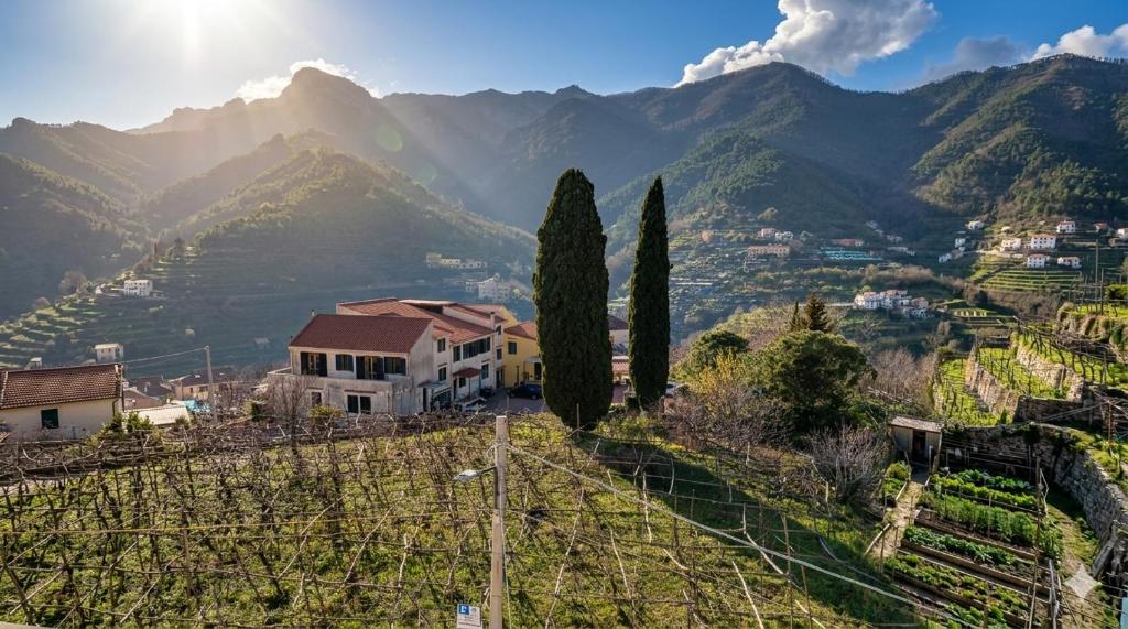 a house on a hill with mountains in the background at Putechella Slow Living Retrait in Tramonti