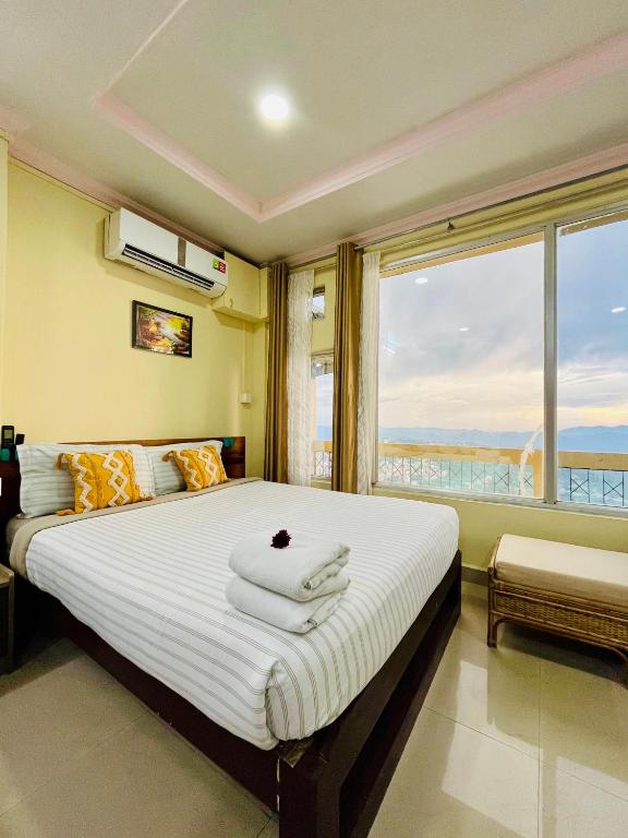 a bedroom with a large bed with a large window at Aizawl Hotel in Āīzawl