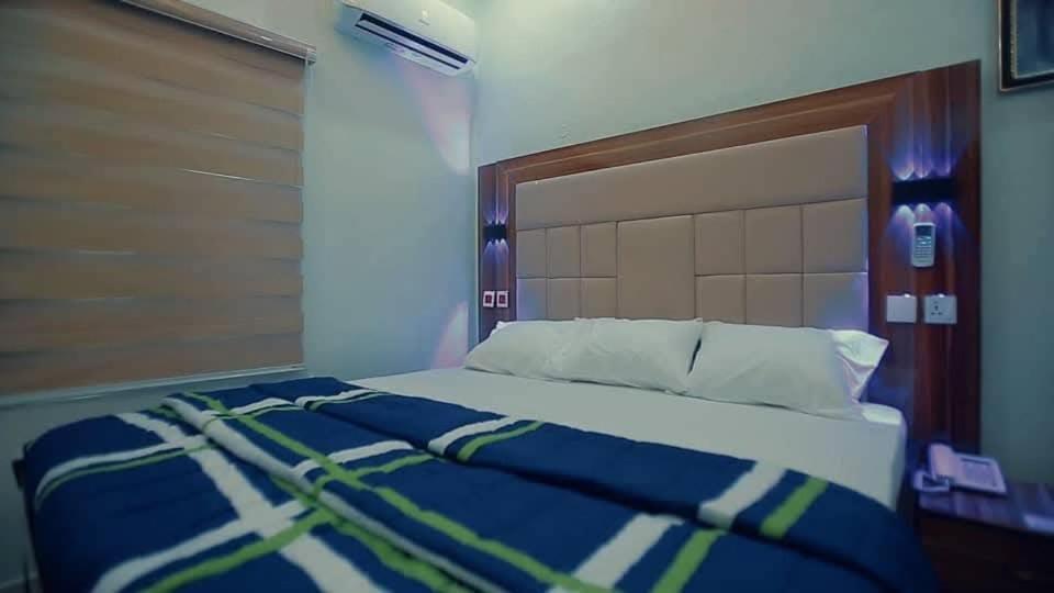 a bedroom with a bed with a blue and green comforter at Riverleaf Hotels and Suites in Asaba