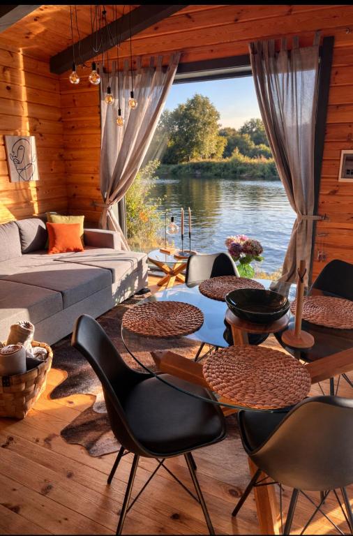 a living room with tables and chairs and a view of a river at Paul Lake Escape Residence in Novosëlki