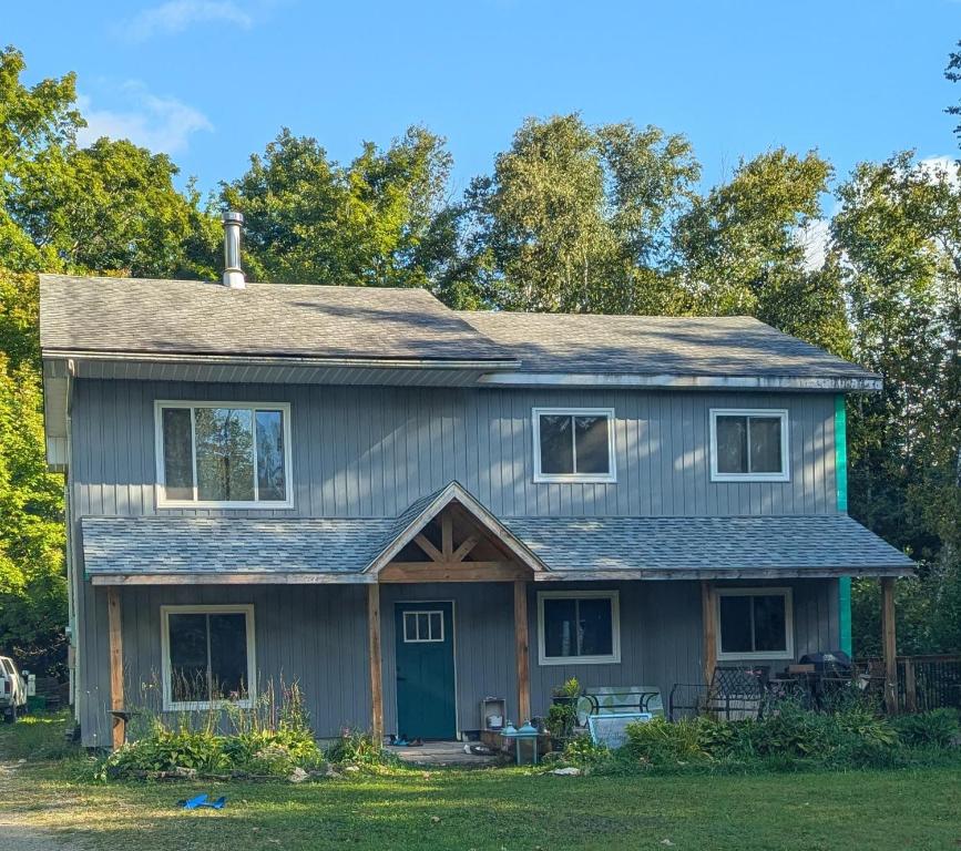 a gray house with a blue door at Larkwhistle Sauna Chickens Near BEACHES in Wiarton