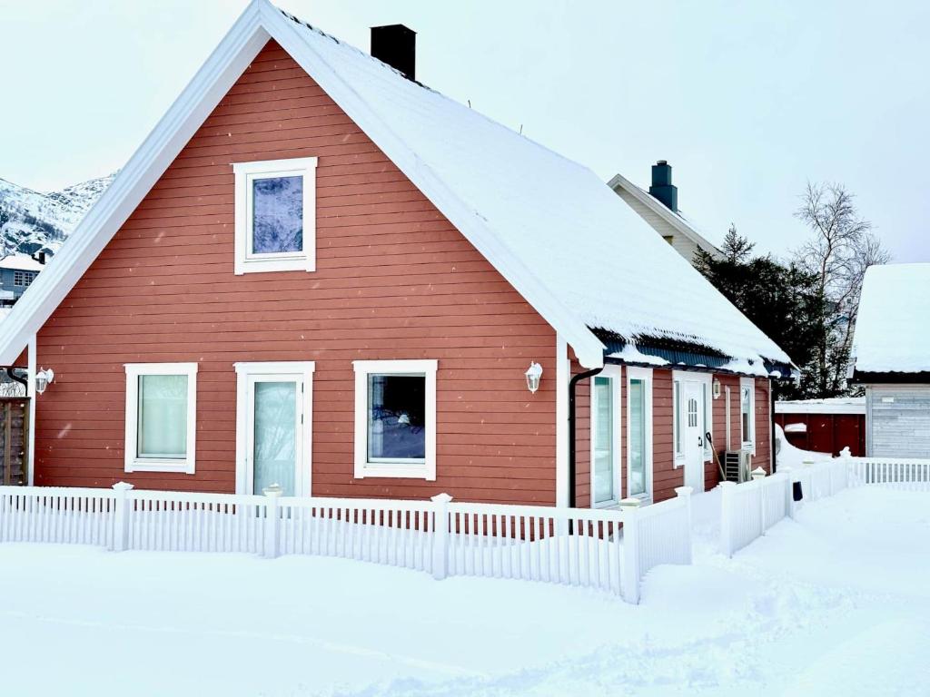 a red house with a white fence in the snow at Arctic Getaway Sørvågen - King Crab Welcome Gift in Sørvågen