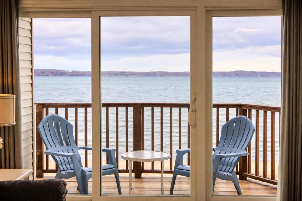 two chairs and a table on a balcony with the water at Beachside 218 Luxury Condo on the Beach in Traverse City