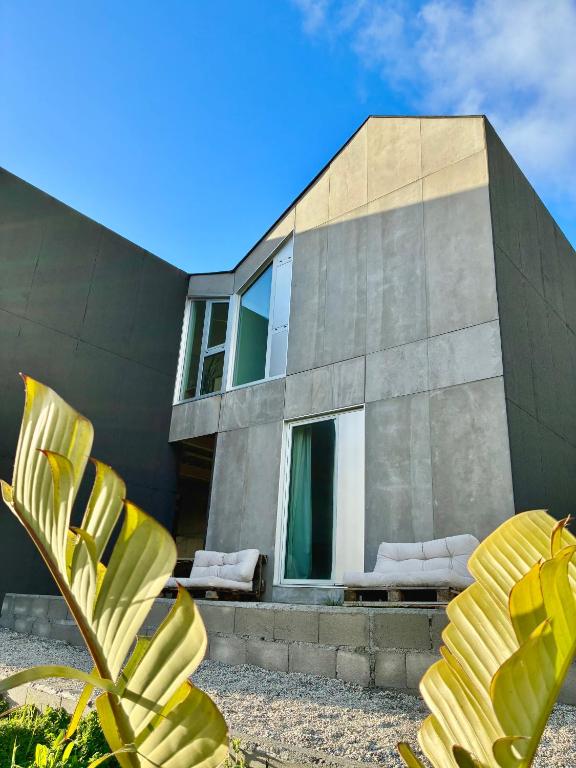 a modern house with a yellow plant in front of it at UMI surf yoga house Doniños beach in Ferrol