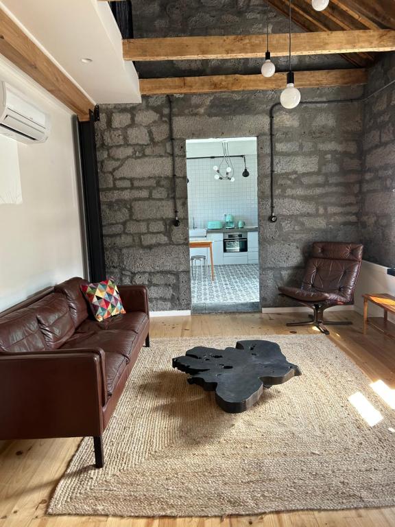 a living room with a leather couch and a table at Cá Por Casa Pico-Criptoméria in Prainha de Baixo