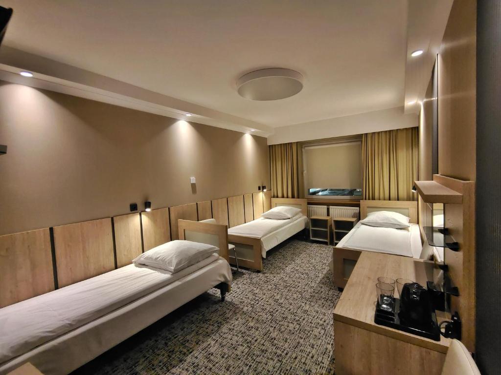 a hotel room with two beds and a desk at Pensione Antonio - Klimatyzowane Pokoje, Centrum Słupska, Spokojny Hotel in Słupsk