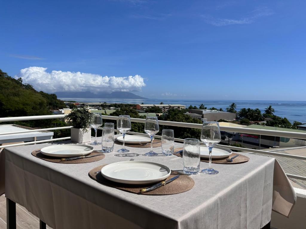 a table with plates and glasses on a balcony at Ora Stay in Papeete
