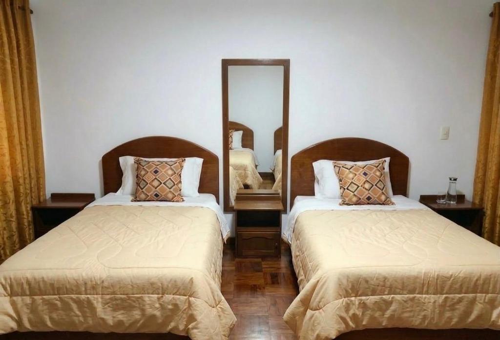 a bedroom with two beds and a mirror at Hostal Chaska Inn in San Antonio