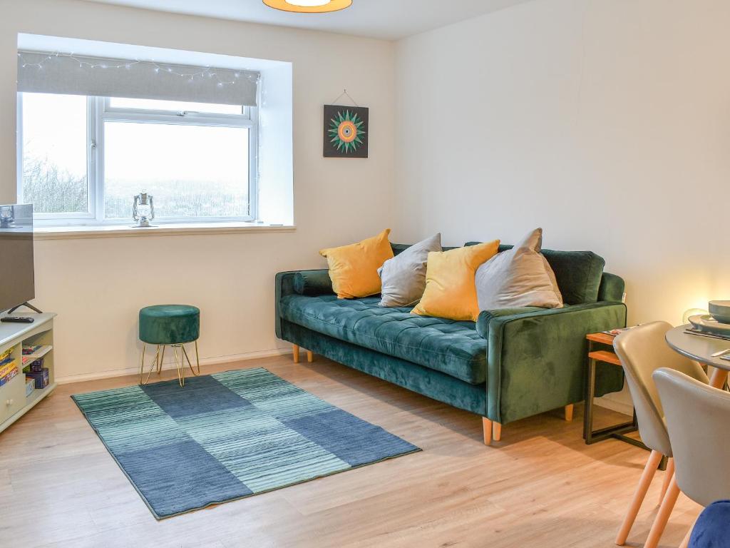 a living room with a green couch and a window at Tankerton Heights in Whitstable