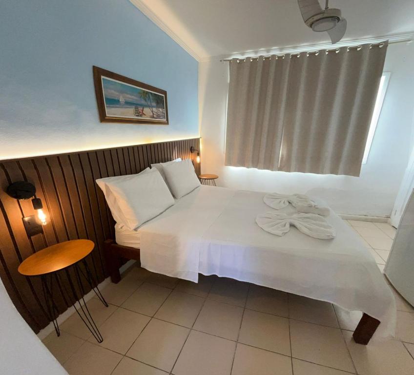 a bedroom with a white bed and a window at Nascimento Suites in Búzios