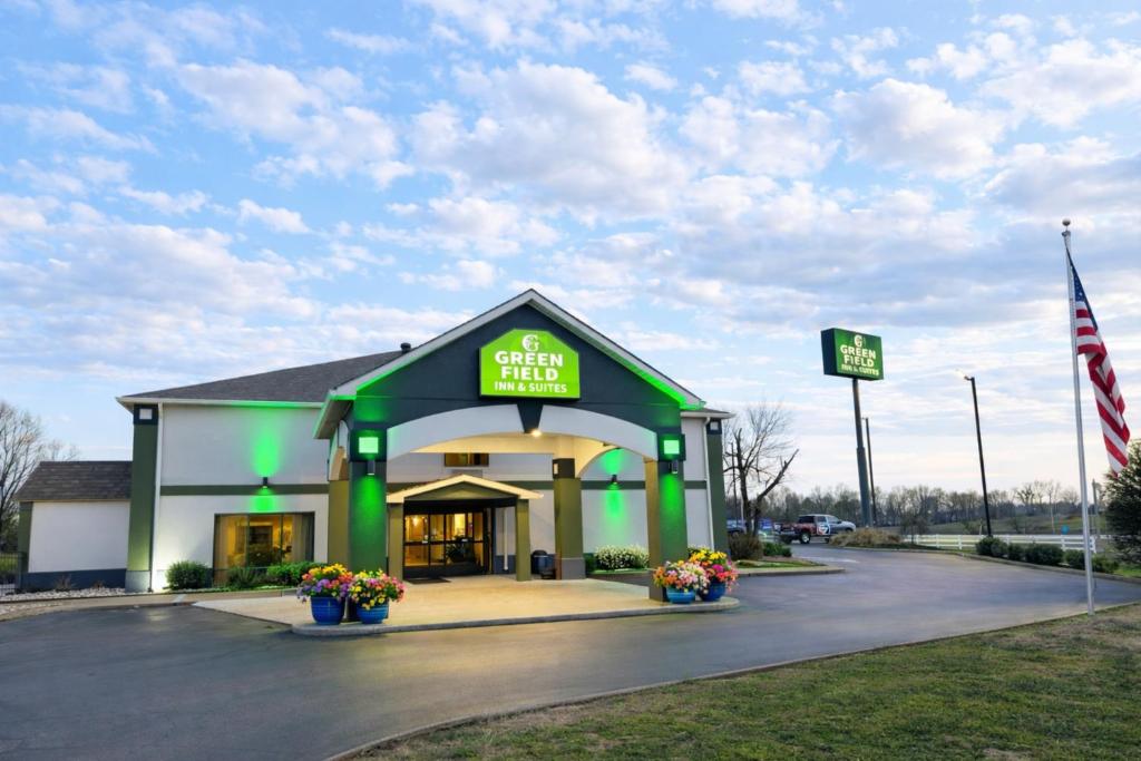 a green and white store with a flag in a parking lot at Greenfield Inn & Suites Owensboro, KY Airport in Owensboro