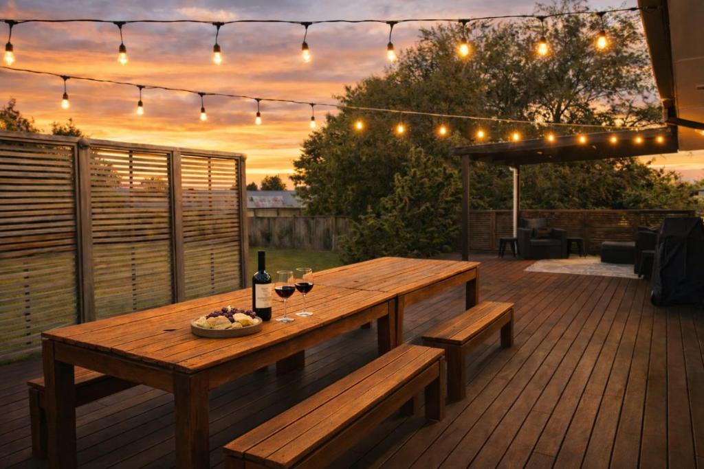 a wooden table and benches on a deck with lights at Redwoods Retreat Rotorua Private 3BR Home in Rotorua