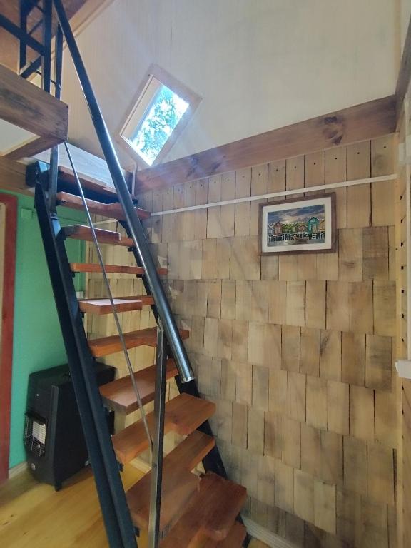 a staircase in a house with a wall of wood at Refugió Chaicura in Notuél