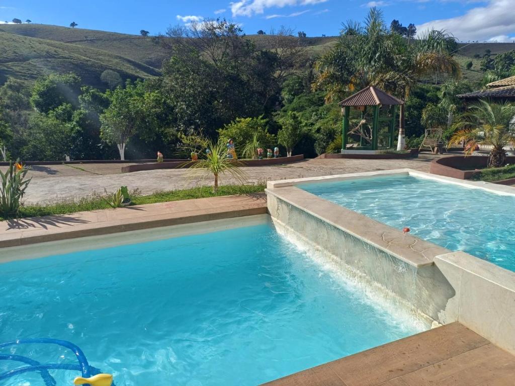 a swimming pool with blue water and a gazebo at Casa ampla e completa para você e sua família in Soledade de Minas