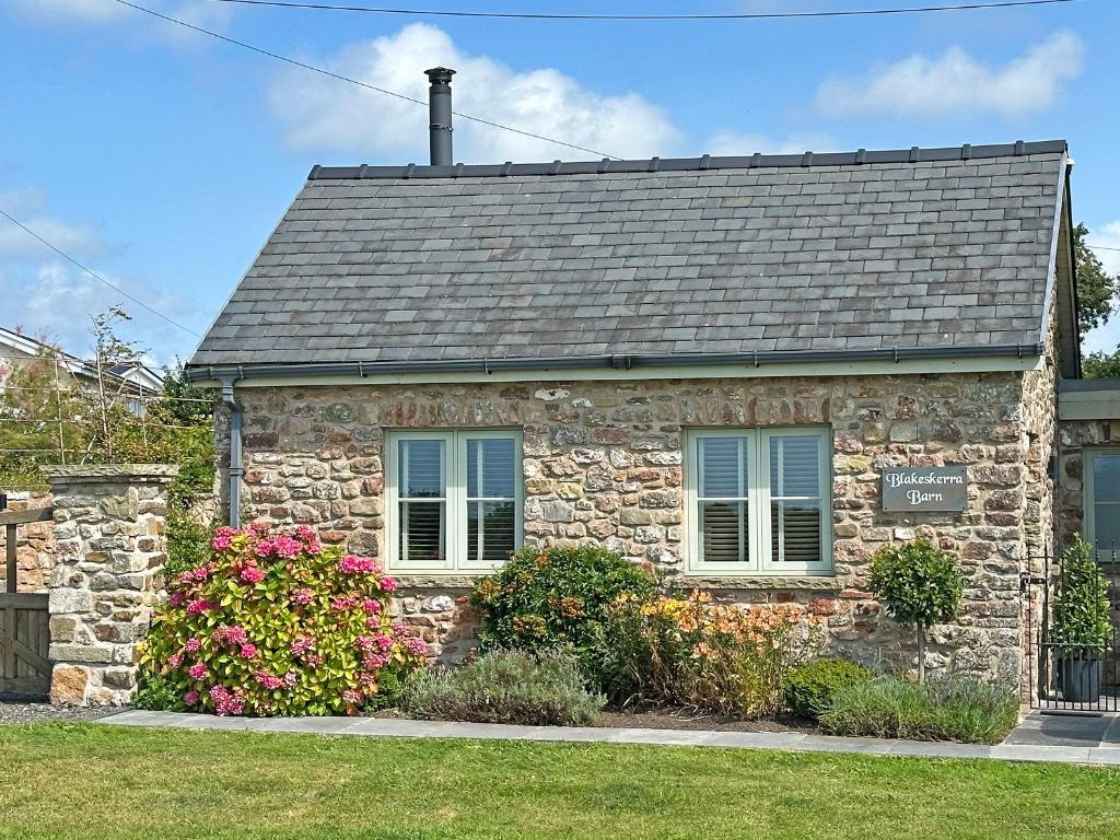 a stone house with flowers in front of it at Blakeskerra Barn in Kenfig