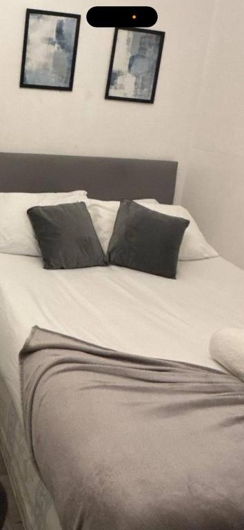 a white bed with two pillows on top of it at Self-contained Studio near Tottenham Hotspurs stadium in London