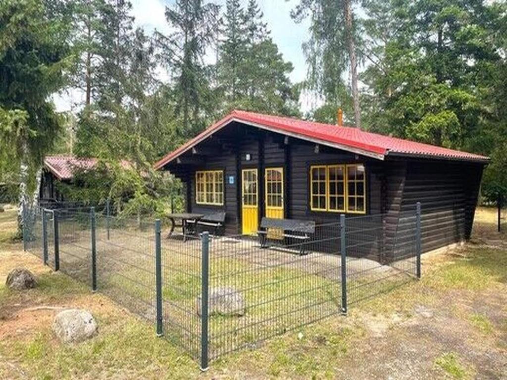 a small cabin with a fence in front of it at Bernsteinsee Home and Ferien Forest Chalet in Sassenburg