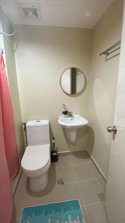 a bathroom with a toilet and a sink and a mirror at B4B Staycation Avida Aspira in Cagayan de Oro