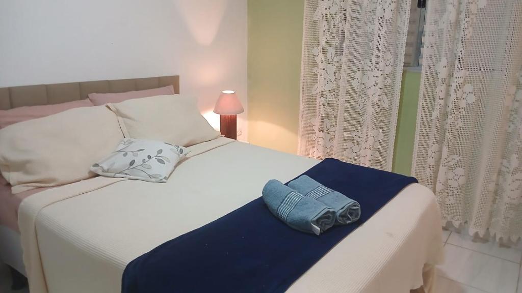 a white bed with a blue towel on it at Hospedagem da Lu in Paraty