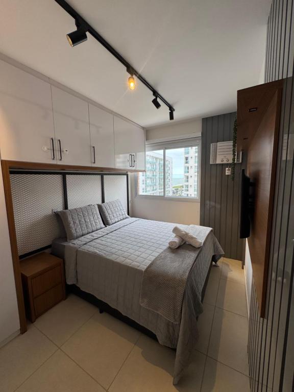 a bedroom with a bed and a large window at Apartamento Moderno uma quadra do mar in Vila Velha