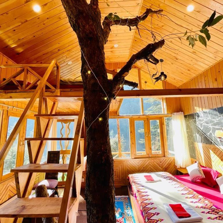 a tree in a room with a bunk bed at Hideaway Tree House in Jibhi