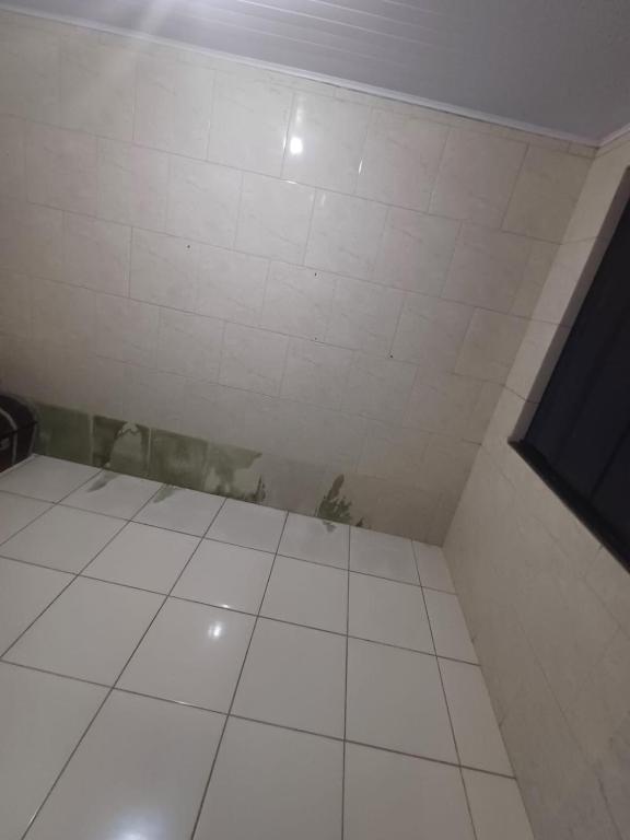 a room with a white tiled floor and a wall at Casa moto gp in Goiânia