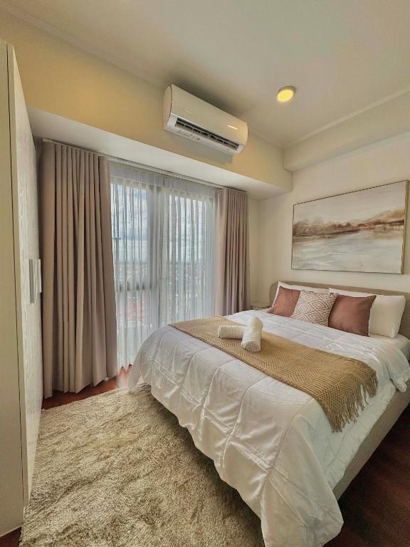 a bedroom with a large bed and a large window at Ivory Davao Condotel near DMSF in Davao City