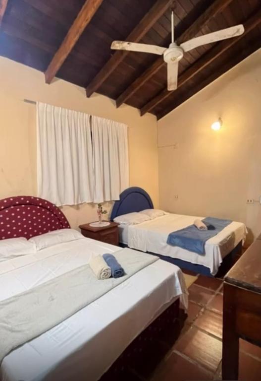 a bedroom with two beds and a ceiling fan at Quinta Arce - Refugio Natural in Trinidad