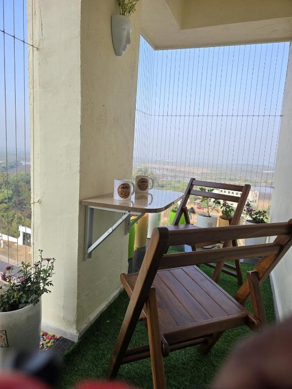 a balcony with two chairs and a table with two cups at Sherans Cottage in Umargām