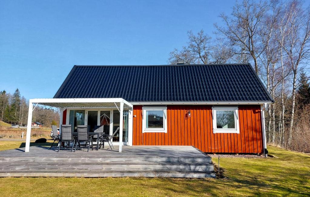 a small red house with a deck and chairs at Amazing Home In Slättåkra in Slättåkra