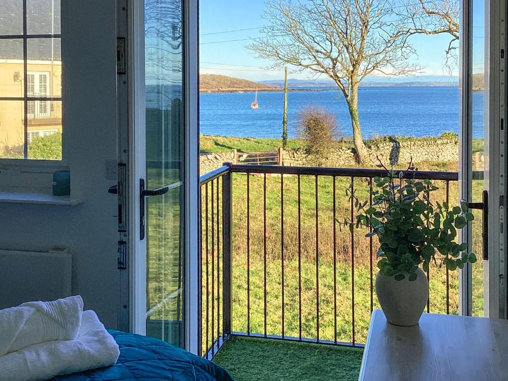 a bedroom with a balcony with a view of the ocean at Seascape in Garlieston