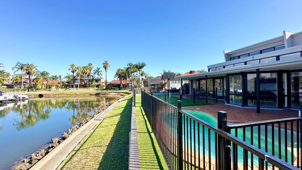 a building with a fence next to a river at Lakefront 6B4B House by GoodLive in Patterson Lakes