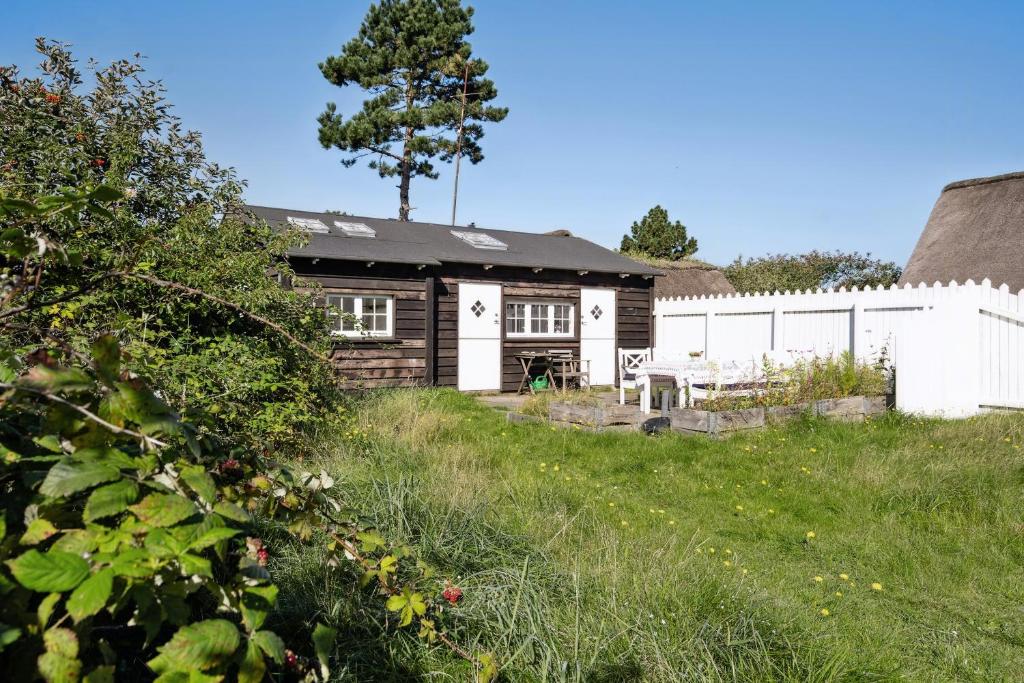 a small wooden house with a white fence at Charming Tiny House In Sønderho in Fanø