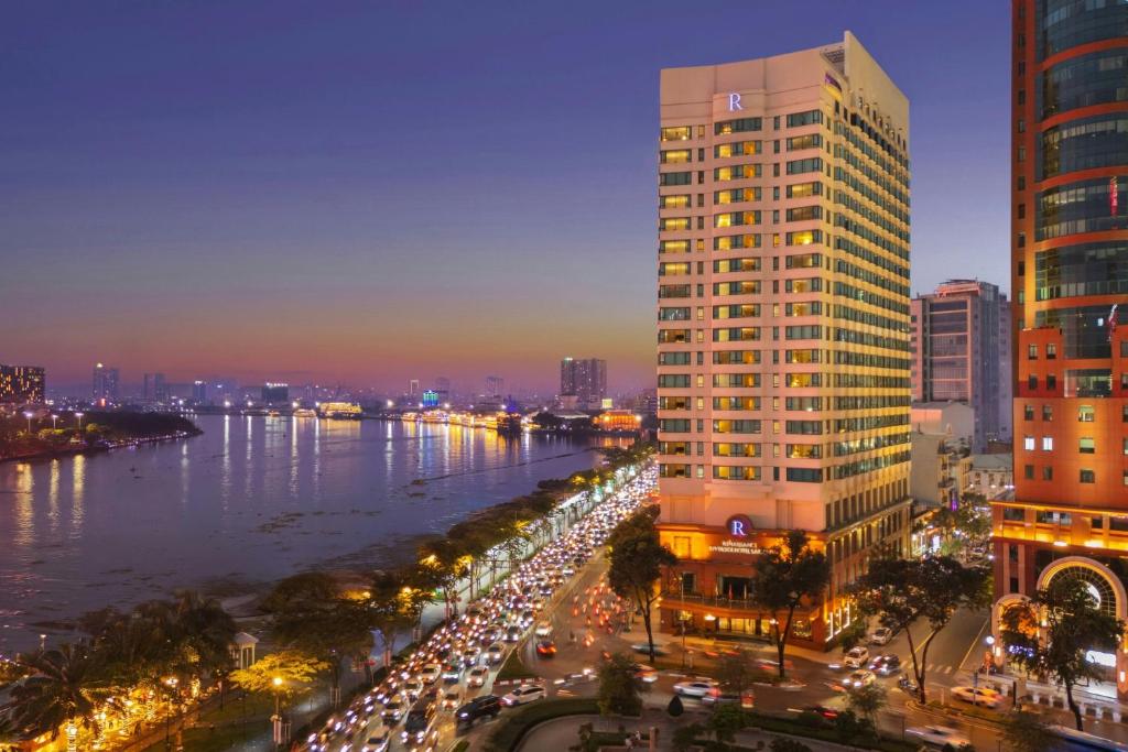 a city with a tall building next to a river at Renaissance Riverside Hotel Saigon in Ho Chi Minh City