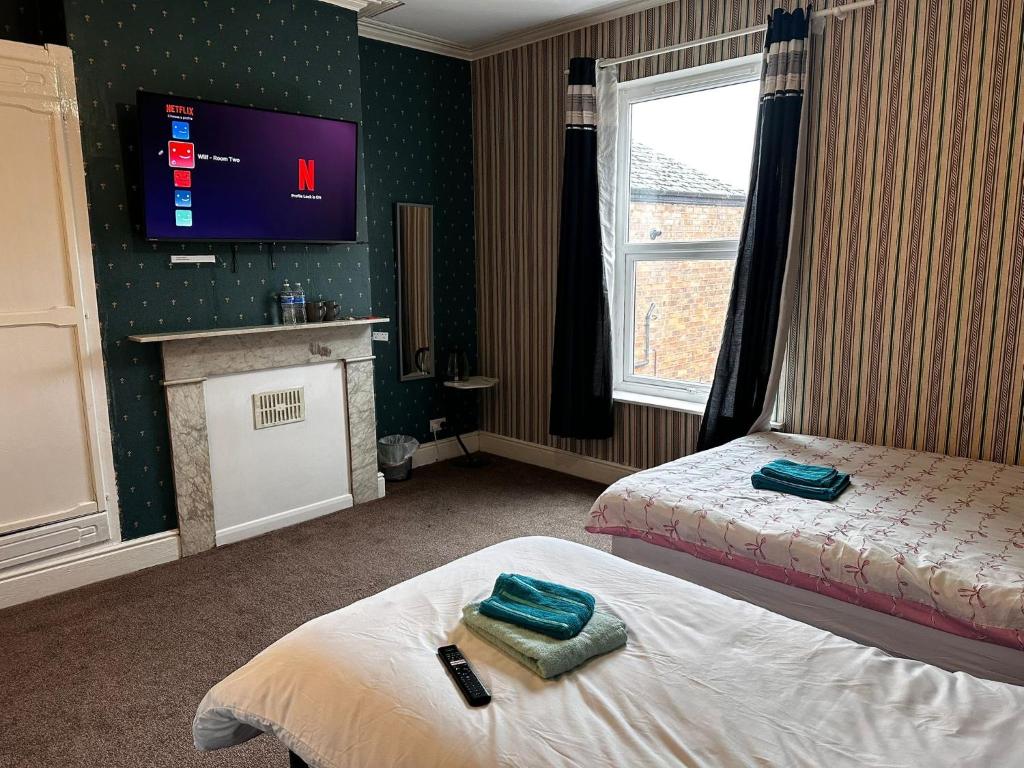 a hotel room with two beds and a tv at Near city centre, Derby train station and royal Derby hospital in Derby